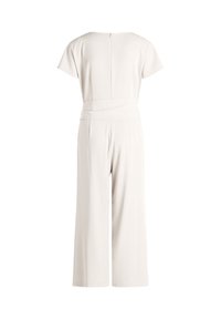Vue de dos d'une combinaison pantalon beige clair à jambes larges avec manches courtes et ceinture, présentée sur un fond blanc uni.