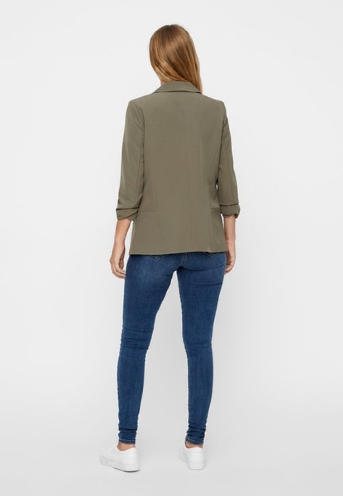 Oliven grøn blazer med skræddersyet pasform, opsmøgede ærmer og bagventilation, kombineret med mørkeblå skinny jeans og hvide sneakers.