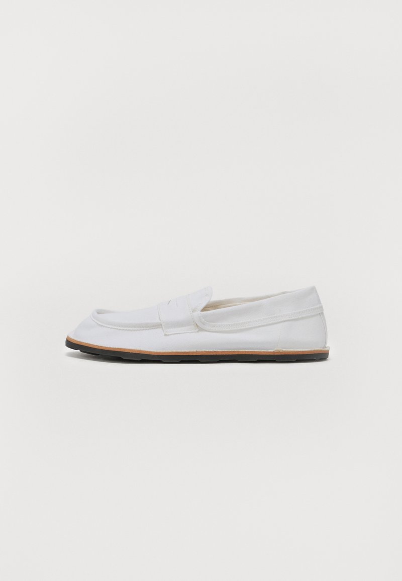 Hvid lærred slip-on sko med en rund tå, minimal syning og en brun gummisål. Designet til afslappet brug.