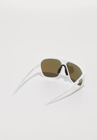 Sonnenbrille mit einem weißen Kunststoffrahmen, braun getönten Gläsern und flexiblen, geraden Schenkeln. Verfügt über eine strukturierte Grifffläche auf dem Nasenpad.