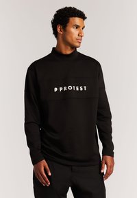 Schwarzer Pullover mit hohem Kragen, der den weißen Text "PROTEST" zentriert auf der Brust trägt. Hergestellt aus glattem, dehnbarem Stoff.
