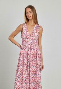 Abito lungo con scollatura a V profonda, texture plissettata e un motivo floreale nelle tonalità di rosa, viola e rosso. Design fluido con vita aderente.