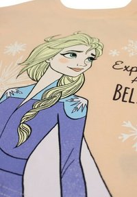 T-shirt pêche avec un graphique d'un personnage aux cheveux blonds et une tresse, portant des vêtements bleus et violets, avec des accents de flocons de neige et du texte.