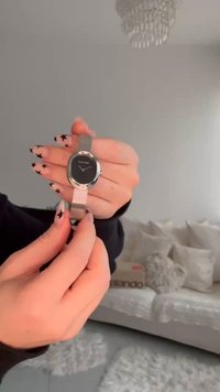 Silberne Maschenbanduhr mit rundem schwarzem Zifferblatt, minimalistischen silbernen Akzenten und dem sichtbaren Markennamen "Calvin Klein". Texturiertes Armband-Design.