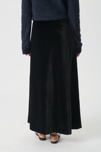 Črna, dolga plišasta krila z gladko teksturo. Nosi se z temnim puloverjem z dolgimi rokavi. Ima preprost, tekoč dizajn.