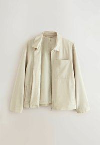 Chaqueta beige clara hecha de tela texturizada. Presenta un cuello, un bolsillo delantero y cierre de cremallera. El interior es suave y totalmente forrado.