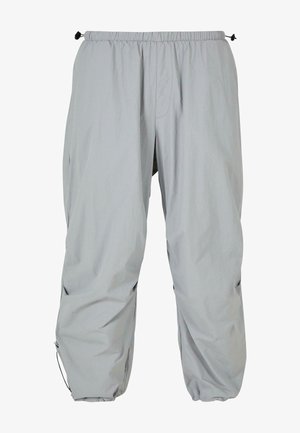 Lys grå, letvektige bukser med elastisk midje og justerbare snorer ved mansjettene. Har side lommer og en jevn tekstur.