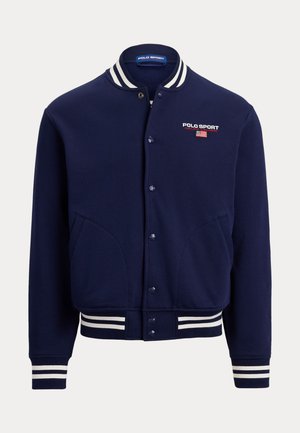 Temno modra varsity jakna z rebrastim ovratnikom in manšetami z belimi črtami, zapiranjem na sponke in vezenim napisom "Polo Sport" na prsih.