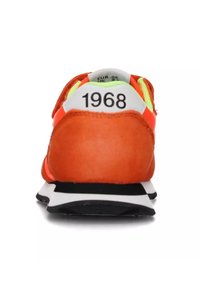 Oranje sportshoe met een bovenwerk van suède, een wit en zwart loopvlak en een groene accent bij de hiel. Nummer "1968" op de achterkant.