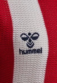 Rødt og hvidt stribet åndbart stof med navyblåt Hummel-logo broderet i midten.