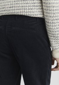 Morske corduroy hlače z teksturirano površino, slim fit, zadnjimi žepi in kontrastnim teksturiranim pletenim puloverjem.