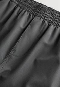 Graue Sportshorts mit elastischem Bund und seitlichem Taschen-Detail, aus glattem, leichtem Stoff und mit gesteppten Akzenten.