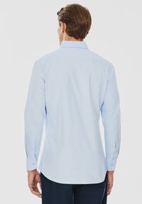 Jasnoniebieska koszula z długim rękawem, z mankietami na guziki, klasycznym kołnierzykiem i gładkim materiałem. Posiada prosty dół i subtelne detale przeszycia.