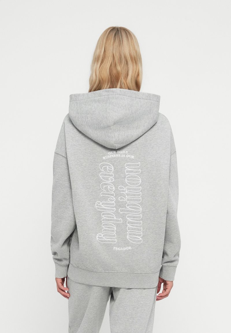 Sweatshirt cinza com uma grande impressão em branco nas costas, apresentando uma tipografia ondulada. Feito de um tecido suave, com um corte relaxado e capuz com cordão.