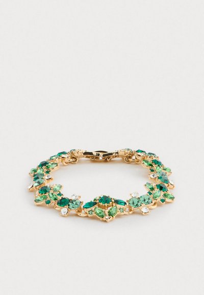 Bracelet doré avec des pierres gemmes vertes et blanches disposées en motifs floraux, sécurisé par un fermoir, exposé sur un fond blanc.