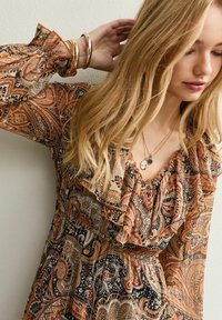 Bruine jurk met een patroon, lange mouwen, gerimpelde halslijn, gemaakt van een lichtgewicht stof, met ingewikkelde paisley ontwerpen en een getailleerde taille.