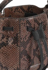Een bucket bag met een bruin en zwart slangenprintpatroon, leren accenten en een trekkoordsluiting. Het merklogo is zichtbaar aan de onderkant.