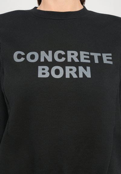Felpa nera a girocollo con bold testo grigio "CONCRETE BORN" centrato sul petto.