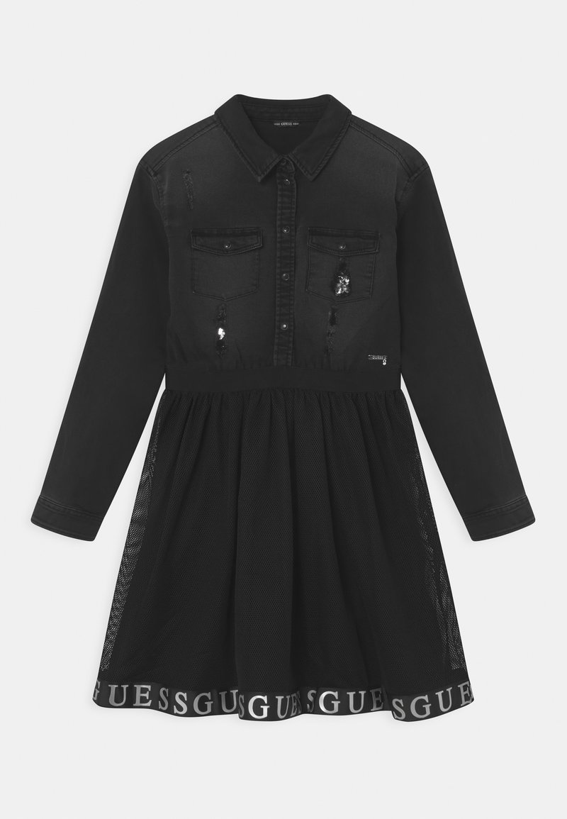 Svart denimklänning med lång ärm, knapppchar för, två bröstfickor och meshkjol. Har "GUESS"-logotypen på fållen. Slitage detaljer.