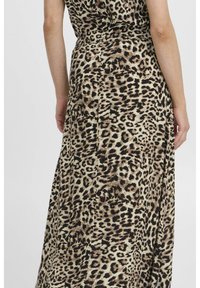 Robe maxi à imprimé léopard avec une taille cintrée, un tissu fluide et un mélange de couleurs marron, noir et crème dans un design texturé.