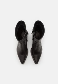Bottines en cuir noir avec bout pointu, texture lisse et fermetures éclair sur les côtés. Intérieur doublé de tissu doux pour plus de confort.