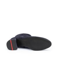 Suela de zapato de tacón de ante azul marino con una superficie de goma negra texturizada y una franja roja horizontal en el tacón.