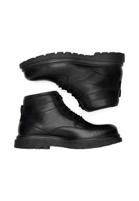 Čierne kožené členkové topánky s robustnou gumovou podrážkou, šnurovací dizajn a jemné šitie. Ploché podpätky a hladká textúra.