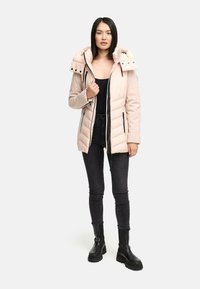 Ljusrosa pufferjacka med huva, som har dragkedja fram, diagonalt quiltat mönster och svarta dragkedjefickor. Kombination med mörka jeans och stövlar.