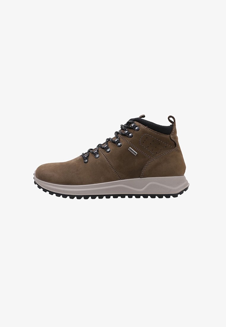 Bota de senderismo marrón con cuello acolchado negro, ojales de metal, suela gruesa con dibujo y pestaña de tela en el talón, vista lateral sobre fondo blanco.