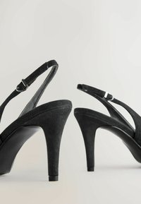 Sandale cu toc înalt din suede negru, cu o curea subțire la gleznă și vârf ascuțit. Tocurile sunt ușor curbată, având un interior neted de culoare neagră.