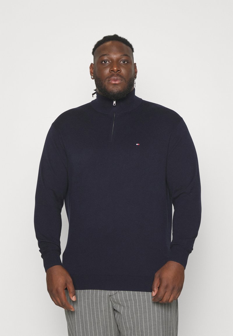 Pull à zip marine avec manches longues, poignets et ourlet côtelés. Présente un petit logo sur la poitrine. Fabriqué en tissu lisse et doux.