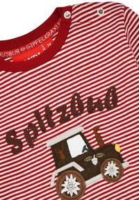 Rot-weißer gestreifter Shirt mit der Aufschrift "Spitzbub" in braun aufgestickt, dazu ein braunes Traktorgrafik und weiße Blumemotive auf den Rädern.