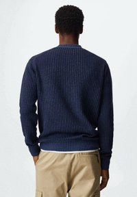 Maglione lavorato a maglia blu navy con un motivo a coste testurizzato, colletto rotondo e maniche lunghe, completato da un orlo aderente.