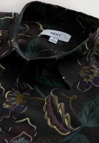 Black shirt featuring a floral pattern in shades of purple, green, and yellow. Includes a buttoned collar and brand label inside.