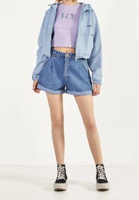 Light blue hooded jacket, lilac crop top with floral embroidery, high-waisted denim shorts, and black high-top sneakers with white laces.