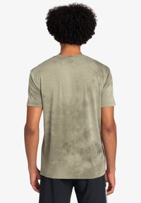 Camiseta verde oliva hecha de una tela suave, con un corte relajado, cuello redondo y un sutil patrón de tie-dye en la parte posterior.