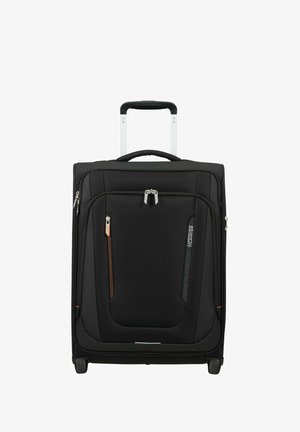 Valise souple noire à position verticale avec poignée télescopique, poches frontales zippées et deux roues pour rouler.