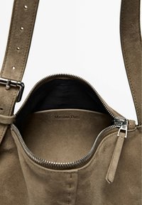 Borsa in suede beige con hardware in argento, chiusura con zip e un'esterno testurizzato. Etichetta "Massimo Dutti" visibile all'interno.