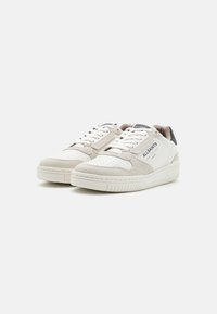 Weiße Sneakers mit einem Obermaterial aus strukturiertem Wildleder und glattem Leder, ausgestattet mit einem Durchbruchs-Design, Schnürsenkeln und einem dezenten Logo-Akzent.