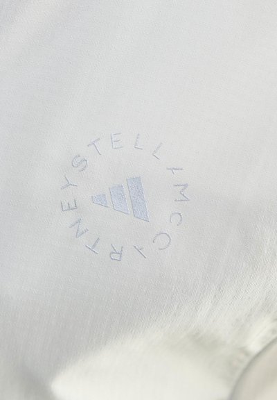 Бяла тъкан със сив лого, показващо три диагонални ивици и текст "STELLA MCCARTNEY", подреден в кръг.