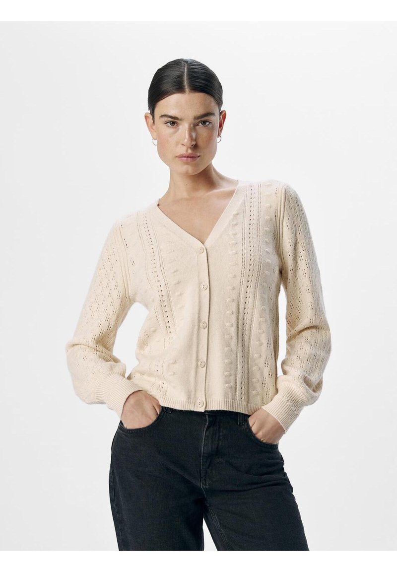 Knit cardigan in cream with a V-neck, front buttons, and textured patterns. Long sleeves with ribbed cuffs and a fitted hem.