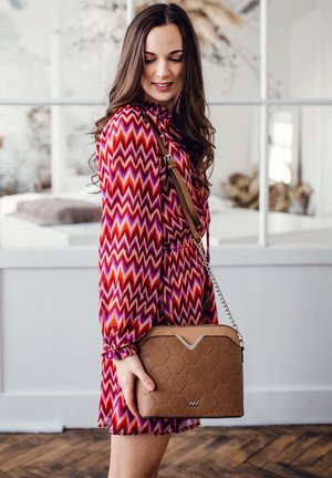 Braune gesteppte Handtasche mit einem silbernen Kettenriemen, die ein geometrisches Design und einen kontrastierenden V-förmigen Akzent oben aufweist.