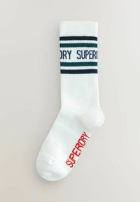 Witte katoenen sok met blauwe en groene horizontale strepen en het "SUPERDRY" logo, rode accent op de teen en een geribbelde textuur.