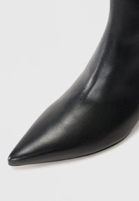 Zwarte leren enkellaars met punten, met een gladde textuur, voorzien van een slanke uitstraling en een ontwerp met hoge hakken.