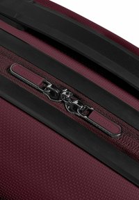 Kastanjebruine harde koffer met een gestructureerd oppervlak, uitgerust met een zwarte rits-handvat en een zilveren rits, gemarkeerd met "REDOLZ."