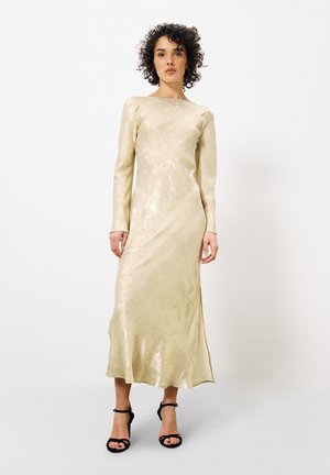 Metallic gold Abendkleid mit langen Ärmeln, tailliertem Oberteil und leichtem Schwung am Saum. Glatte Textur, minimalistisches Design und seitlicher Schlitz.