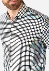 Korte mouw shirt met een zwart-wit vierkant rasterpatroon en iriserende accenten. Knopen aan de voorkant, standaard kraagontwerp.