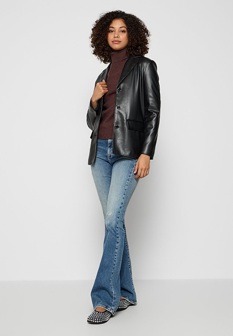 Zwart leren blazer met revers, enkele knoopsluiting en voorzakken, gedragen over een bruine coltrui, gecombineerd met uitlopende denim jeans en geplaatste schoenen.