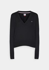 Pull noir à col en V à manches longues avec poignets et ourlet côtelés, présentant un petit logo Tommy Hilfiger sur la poitrine et une étiquette rayée au niveau du col.