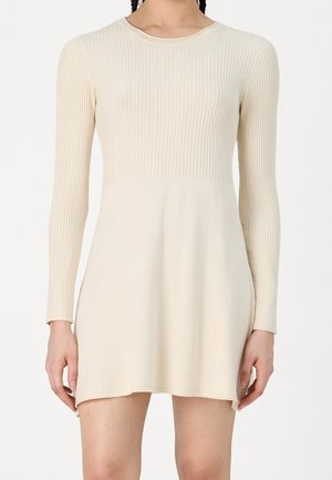 Knit dress in light beige with long ribbed sleeves, round neckline, fitted bodice, and a slightly flared hemline. Soft texture, minimal detailing.